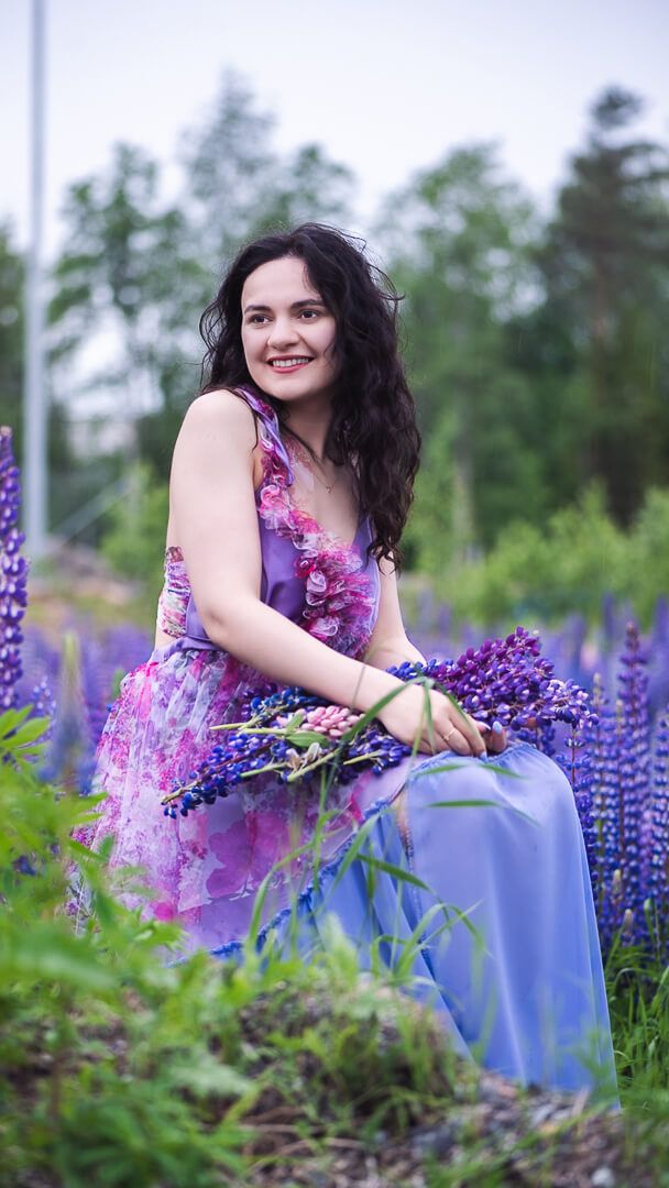 Kukkakuvioinen mekko ja sininen tylliskirtti, sylissä lupiinikimppu