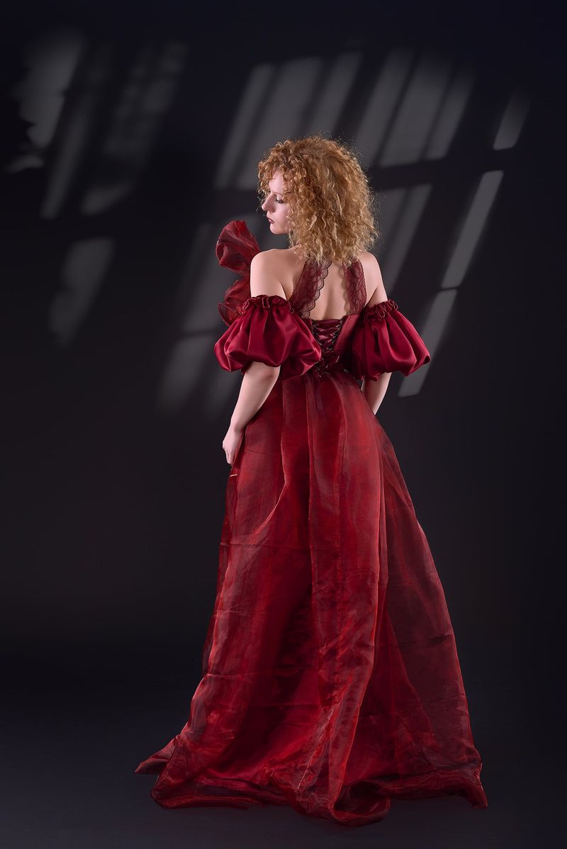 Back view of the red organza gown with lace-up detail and flowing train