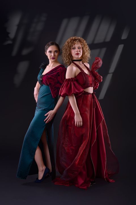 Two evening gowns side by side: teal with a red drape and red organza with puff sleeves